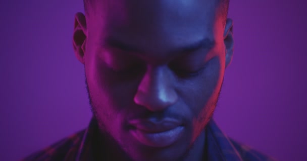 Close up studio portrait of handsome african american man raising face to camera in neon lights, slow motion — Stock Footage Close up studio portrait of handsome african american man raising face to camera in neon lights, slow motion — Stock Video