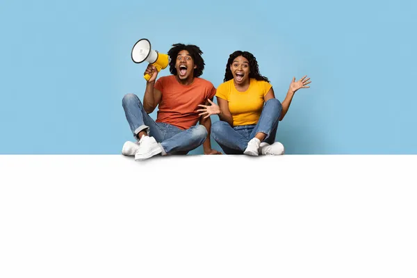 Couple noir émotionnel assis sur une planche horizontale vide pour la publicité — Photo