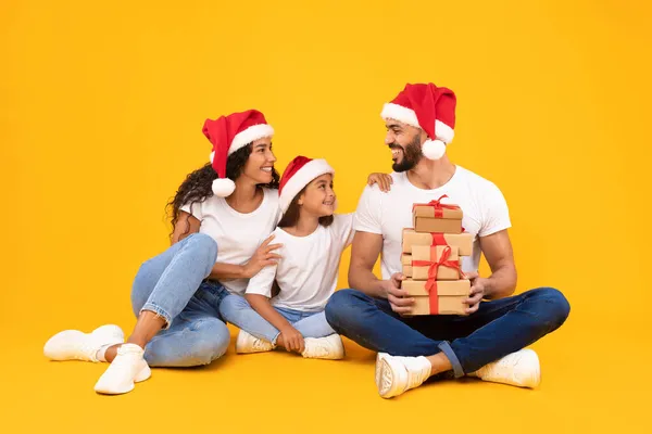 Arab Family Holding Christmas Gifts Boxes Over Yellow Studio Background — Stock Photo, Image