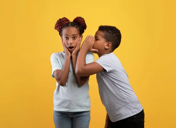 Preto menino irmão compartilhar segredos com seu chocado irmã — Fotografia de Stock