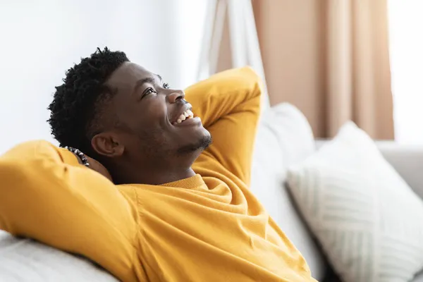 Closeup of cheerful black guy reclining on couch — Stock Photo, Image