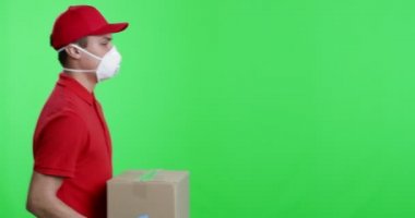 Koruyucu maskeli ve eldivenli kurye paket veriyor.