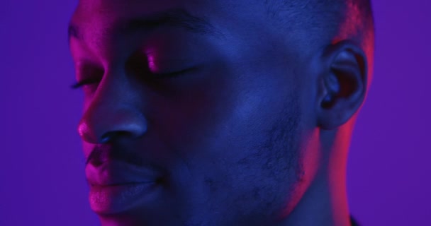 Young positive african american man turning face to camera and widely smiling, neon lights background — Stock Footage Young positive african american man turning face to camera and widely smiling, neon lights background — Stock Video