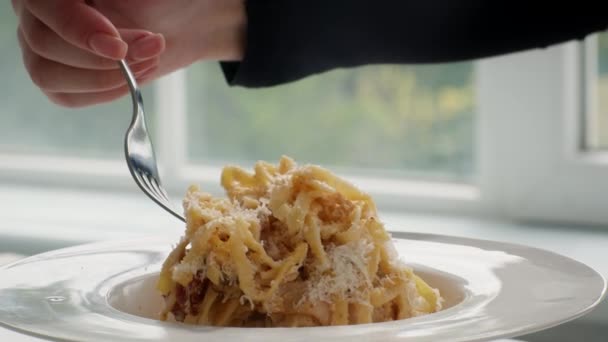Oigenkännlig kvinna äter god pasta med gaffel i köket, närbild — Stockvideo