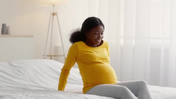 집에서 침대에 앉아 있는 아름다운 젊은 임신 한 흑인 여자의 모습 — 비디오