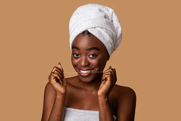 Молодая черная женщина с зубной нитью смотрит в камеру — стоковое фото