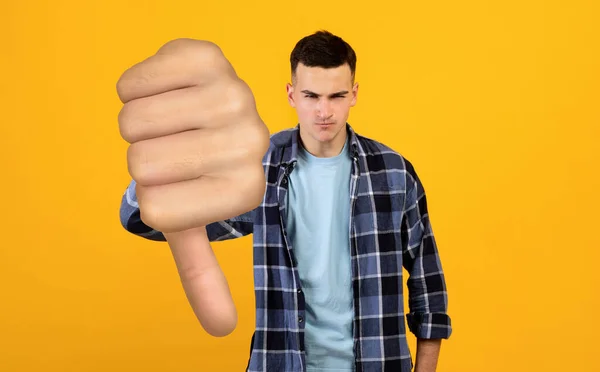 Dühös fiatalember mutatja hüvelykujját le a sárga — Stock Fotó