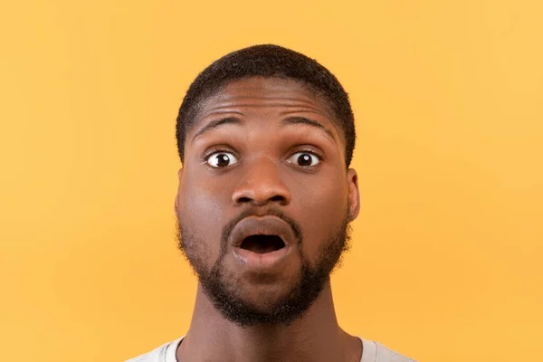 Berita luar biasa. Portrait of black man opened his mouth and eyes in shock, looking at camera over yellow background — Stok Foto