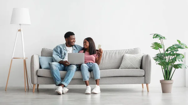 Feliz casal preto usando pc e cartão de crédito em casa — Fotografia de Stock