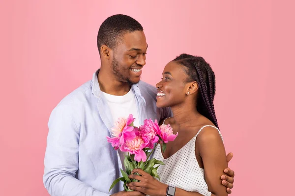 Felice uomo nero fare sorpresa per la donna dando fiori — Foto Stock