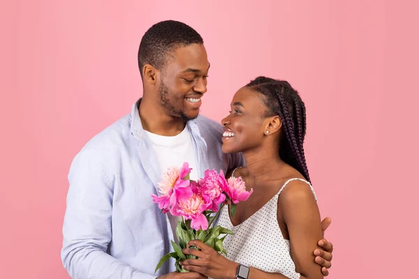 Gelukkig zwart man maken verrassing voor vrouw het geven van bloemen — Stockfoto