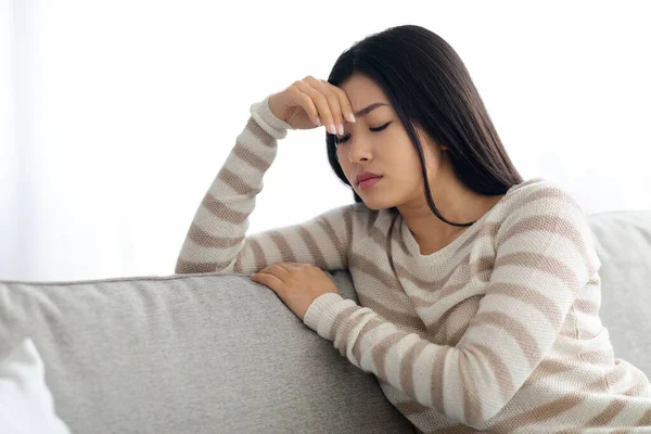 Концепція депресії. Молода азіатка сидить на дивані вдома — стокове фото