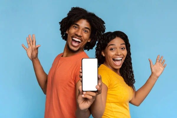 Känslomässiga afrikanska amerikanska älskare visar mobiltelefon, mockup — Stockfoto