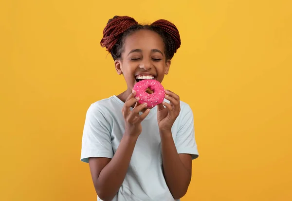 Dolce dente nero ragazza mangiare ciambella su giallo — Foto Stock