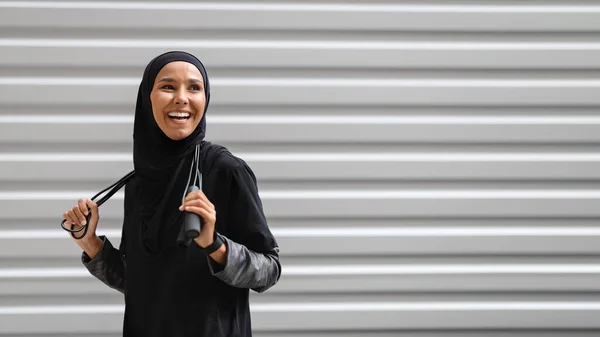 Wanita Muslim muda yang ceria Dalam Sportswear Sederhana Posing Dengan Melewatkan Rope Outdoors — Stok Foto