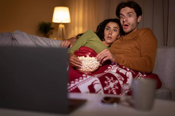 Geschocktes Paar schaut Gruselfilm online auf Laptop zu Hause — Stockfoto