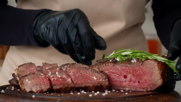 Cocinero irreconocible condimentando la carne con hierbas cocinando carne de res en la cocina — Vídeos de Stock