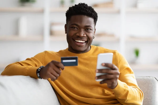 Feliz joven negro hombre usando el teléfono celular y la celebración de la tarjeta de crédito —  Fotos de Stock