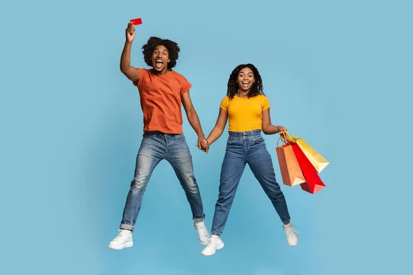 Emocionální černošky pár s nákupními taškami a kreditní kartou — Stock fotografie