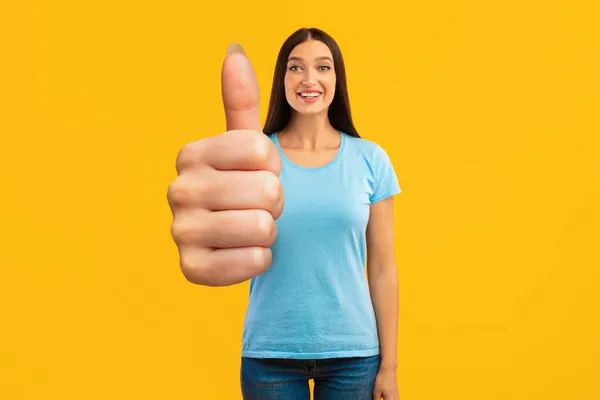 Szczęśliwa kobieta gestykulująca kciuk w górę i uśmiechnięte, żółte tło — Zdjęcie stockowe
