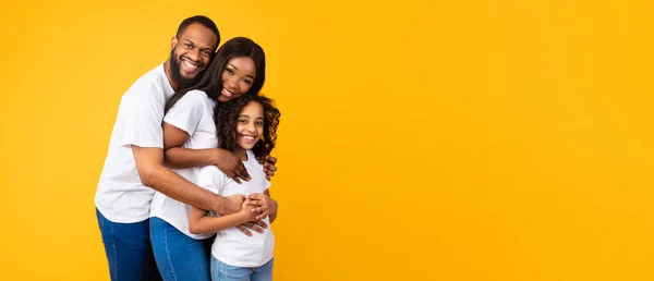 Hombre afroamericano abrazando a su esposa e hija sonriente, panorama — Foto de Stock