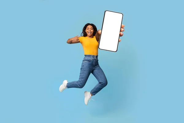 Pozitív afro-amerikai nő mutatja nagy okostelefon üres képernyőn — Stock Fotó
