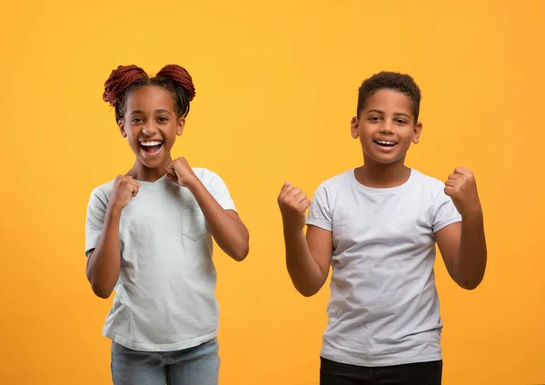 Irmãos negros emocionais comemorando o sucesso no amarelo — Fotografia de Stock