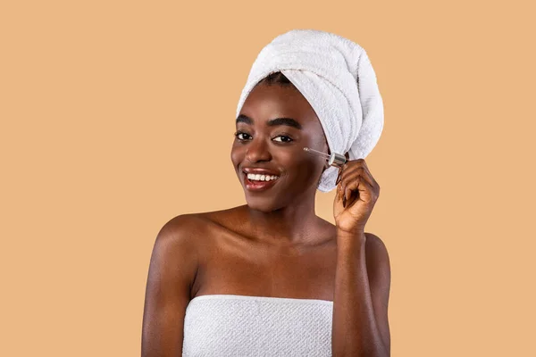 Portret van een lachende zwarte vrouw met serum — Stockfoto
