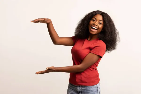 Веселая афроамериканка держит невидимый предмет руками — стоковое фото