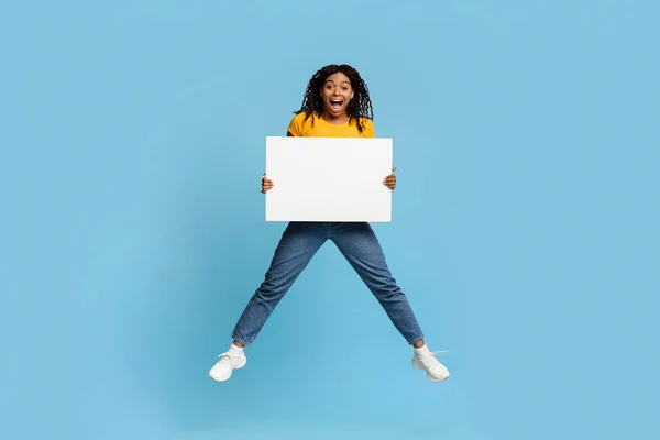 Emocional milenaria mujer negra saltando con un cartel vacío — Foto de Stock