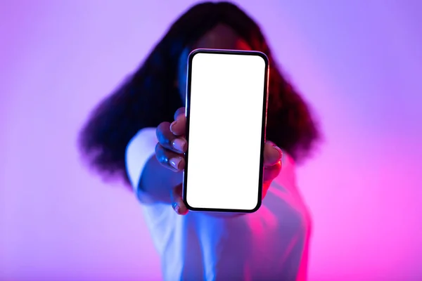 Felismerhetetlen fekete hölgy eltakarja arcát mobiltelefonnal üres képernyővel neon fényben, mockup — Stock Fotó