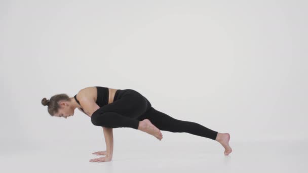 Yoga-Praxis. Junge Frau übt Handstandhaltung und Rückentragen, macht Parivrtta Eka Pada Koundinyasana — Stockvideo