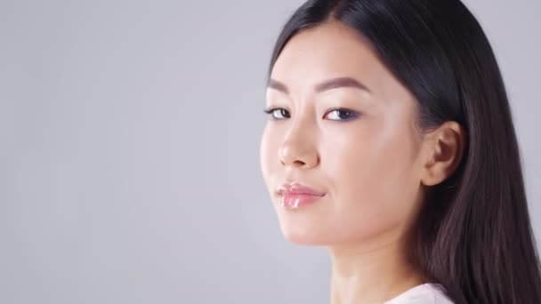 Visão lateral retrato de jovem asiático senhora com cabelo perfeito girando para câmera e sorrindo, espaço vazio, câmera lenta — Vídeo de Stock