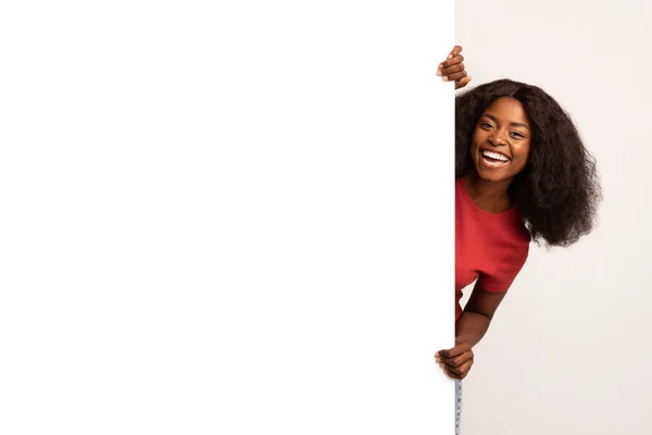 Радостная молодая чернокожая леди стоит на большом белом рекламном щите — стоковое фото