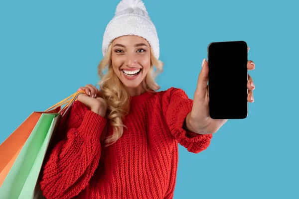Szczęśliwa kobieta trzyma torby shopper pokazując pusty ekran smartfona — Zdjęcie stockowe