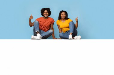 Afro-amerikan aşıklar boş tahtada oturuyor, başparmaklarını kaldırıyorlar.