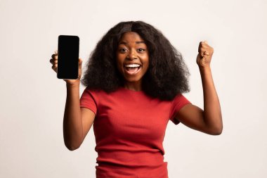 Büyük şans. Aşırı neşeli Afrikalı Amerikalı Kadın Boş Akıllı Telefon Tutuyor ve Başarı Kutlaması