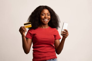 Mobil Bankacılık. Mutlu Afrikalı Güzel Amerikalı Kadın Akıllı Telefon ve Kredi Kartı Tutuyor