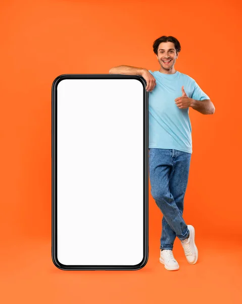 Hombre apoyado en blanco pantalla del teléfono inteligente en blanco que muestra los pulgares hacia arriba —  Fotos de Stock