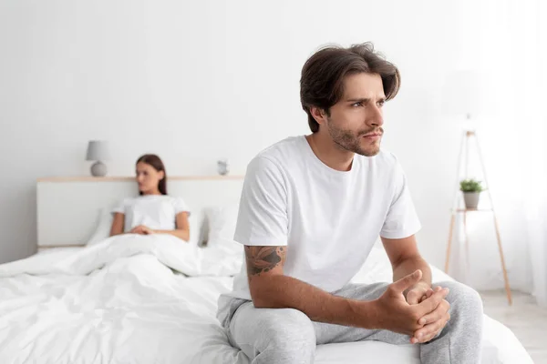 Molesto triste ofendido millennial europeo marido y mujer sentado en la cama ignorándose mutuamente en el interior del dormitorio blanco —  Fotos de Stock
