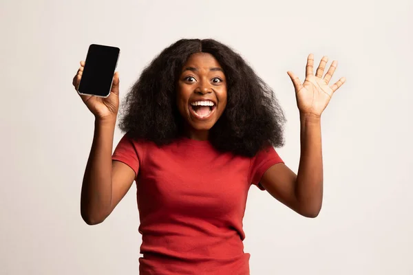 Ena! Amazed Emocional preto senhora segurando Smartphone com tela em branco — Fotografia de Stock