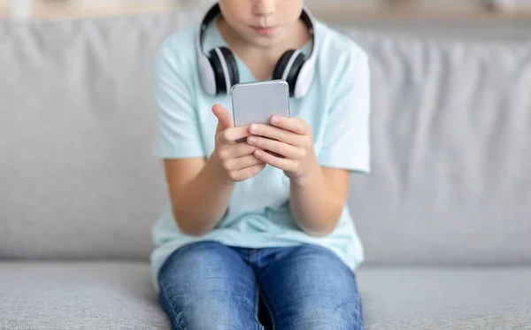 Unrecognizable kid using mobile phone at home