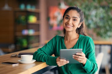 Neşeli Orta Doğulu kadın kafede mola veriyor, ped kullanıyor