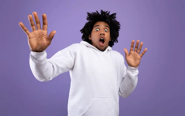 Shocked black teen guy making protection gesture, feeling frightened on violet studio background, panorama — Stock Photo, Image