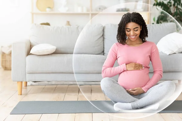 Feliz calma joven afroamericana embarazada mujer meditando y tocando el vientre en la sala de estar — Foto de Stock