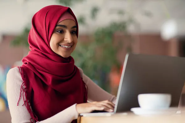 Vallásos muszlim nő gépel a számítógép billentyűzetén, kávézó belső, közelkép — Stock Fotó