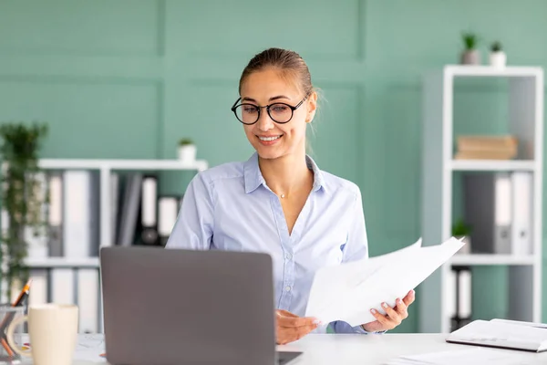 Dizüstü bilgisayarda çalışan ve iş raporlarını tutan meşgul kadın girişimci, ofis içi işyerinde oturuyor. — Stok fotoğraf