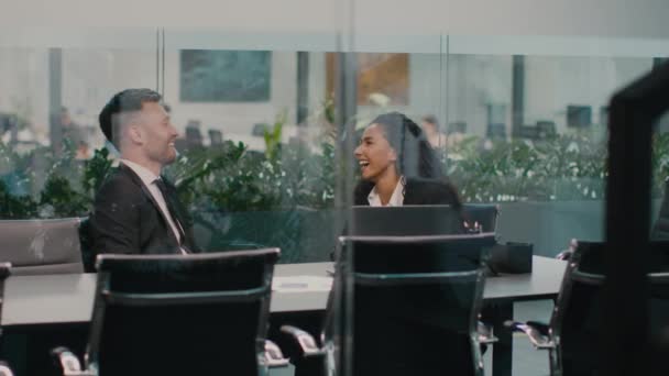 Üzletember és üzletasszony nevetve beszélnek az irodai munkáról. — Stock videók