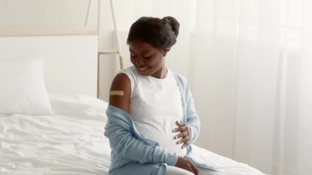 Vaccinerad svart gravid kvinna tittar på arm med självhäftande band efter vaccination — Stockvideo