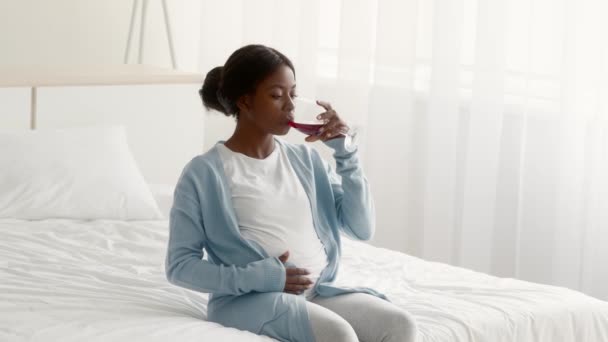 Schwangerschaft und Alkohol. Schwangere schwarze Frau trinkt Rotwein und berührt Bauch — Stockvideo